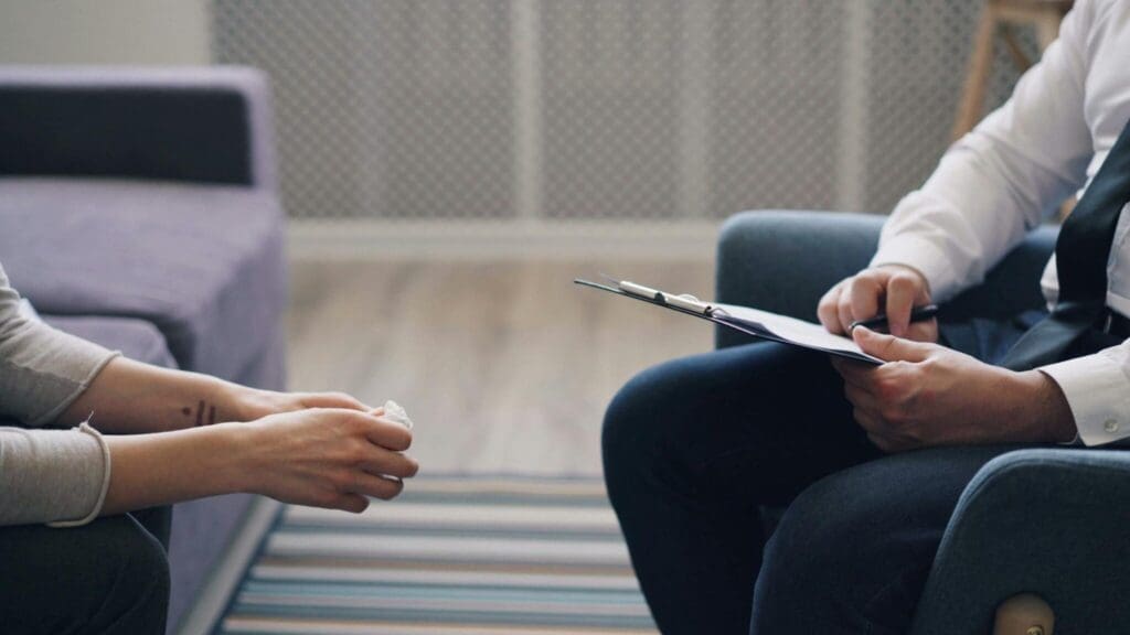 Interaction between a client and therapist during a session, with notes being taken.