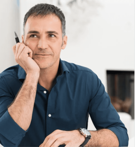 A man contemplating ideas, dressed in a blue shirt, with a relaxed expression.