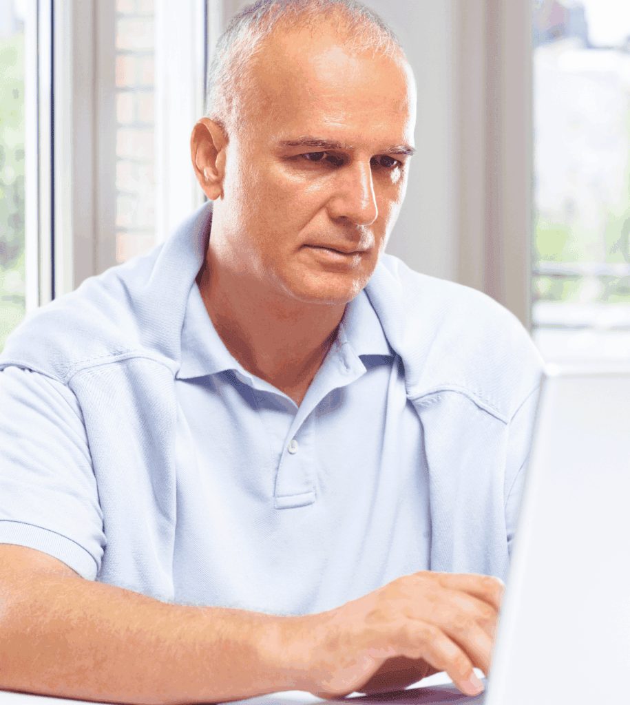A mature gentleman engaged in online tasks on his computer.