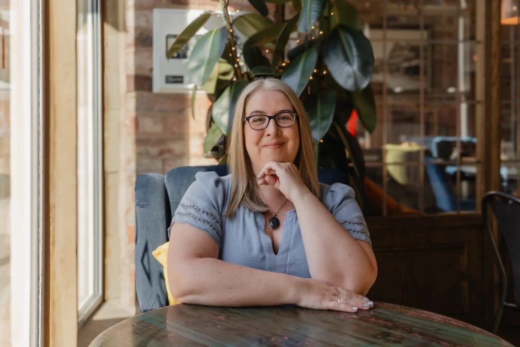 Hannah Paskin in a cafe setting, with a warm atmosphere and decorative plants.