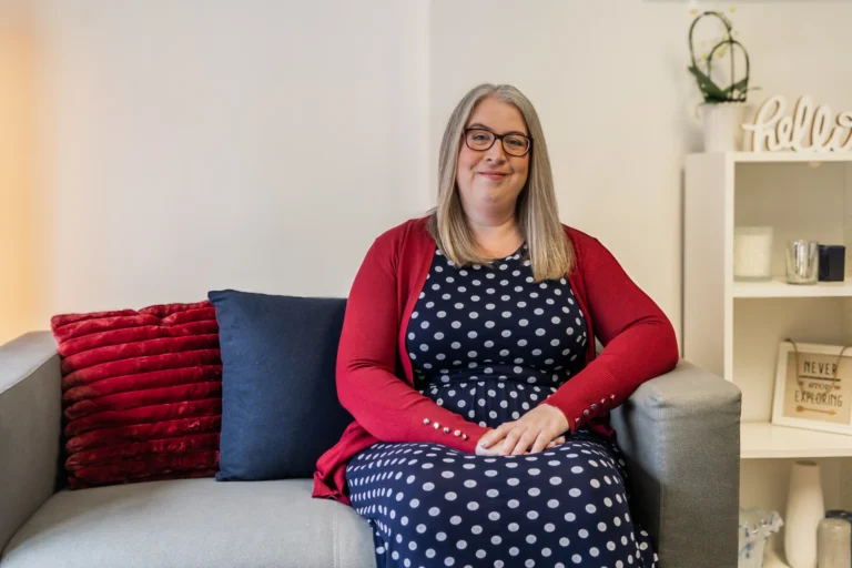A home interior featuring Hannah Paskin on a sofa, surrounded by decorative elements and soft furniture.