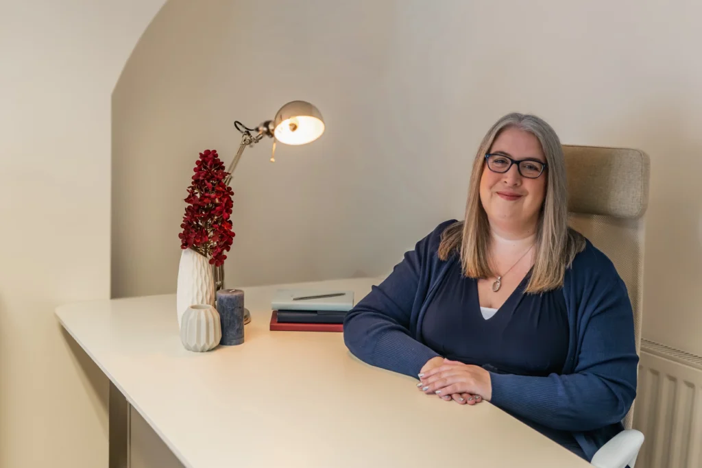 A woman sitting at a stylish home office desk with decorative items.